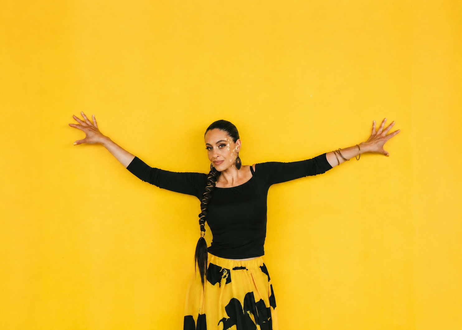Tiffany P. extending her arms against a yellow background